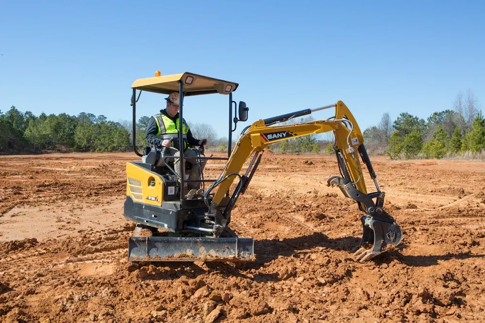 Operator running a rented SANY SY16C mini excavator on a jobsite